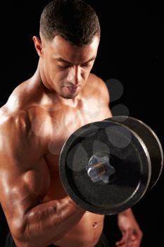 Muscular young man working out with  heavy dumbbell