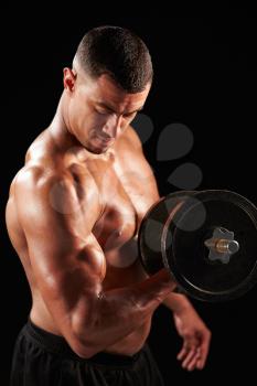 Muscular young man working out with  heavy dumbbell