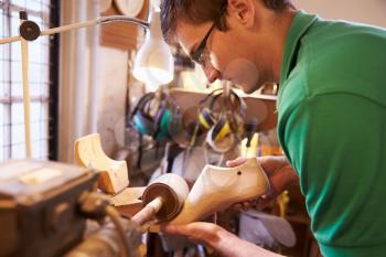 Shoemaker sanding shoe lasts in a workshop