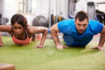 Man and a woman doing push ups at a gym