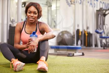 Young woman drinking water in a gym, with copy  space