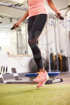 Healthy young woman skipping rope in a gym, crop