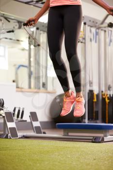 Healthy young woman skipping rope in a gym, crop
