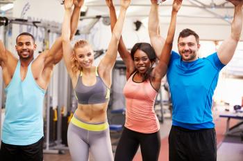 Happy, healthy group of people with arms in the air at a gym