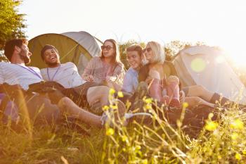 Group Of Friends Relaxing Outside Tents On Camping Holiday