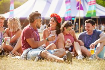 Friends sitting on the grass talking at music festival