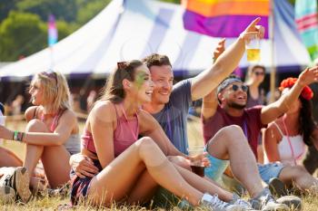 Friends sitting on grass having fun at a music festival