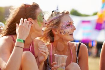 Girl friends wearing face paint at music festival, close up