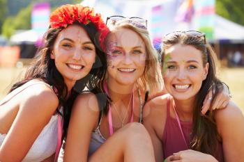 Three girl friends at a music festival looking to camera