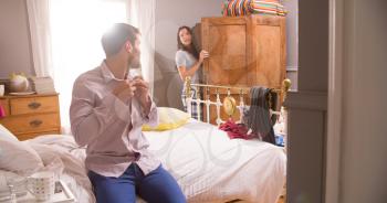 Couple Getting Dressed For Work In Bedroom