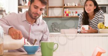 Young Couple Eating Breakfast In Kitchen Together
