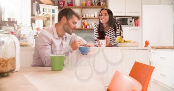 Young Couple Eating Breakfast In Kitchen Together
