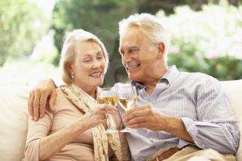Portrait Of Senior Couple Relaxing On Sofa With Glass Of Wine