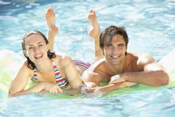 Portrait Of Young Couple Relaxing In Swimming Pool