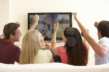 Group Of Friends Watching Widescreen TV At Home