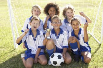 Group Of Children In Soccer Team Celebrating With Trophy