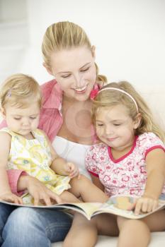 Mother And Daughters Reading Book At Home