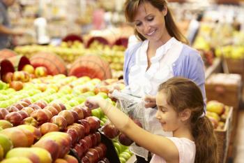 Mother and daughter buying fruit in supermarket