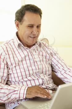 Senior Hispanic Man Using Laptop At Home