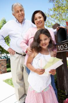 Hispanic Grandparents And Granddaughter Checking Mailbox