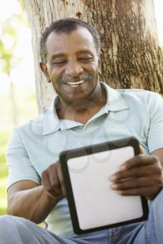 Senior African American Man In Park Using Tablet Computer