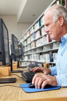 Senior man working on computer in library