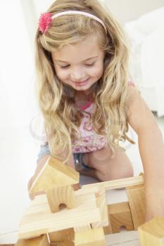 Young Girl Playing With Wooden Building Blocks In Bedroom