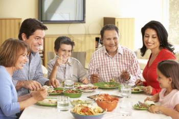 Extended Hispanic Family Enjoying Meal At Home