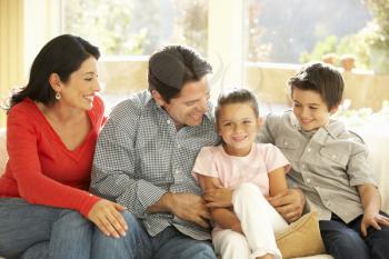 Young Hispanic Family Relaxing On Sofa At Home