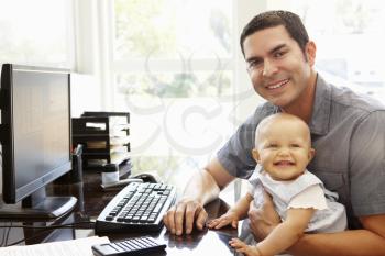 Hispanic father with baby working in home office