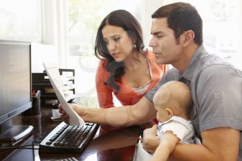 Hispanic couple and baby in home office