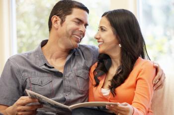 Hispanic couple at home reading magazine