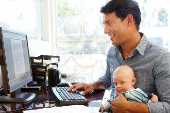 Father working in home office with baby