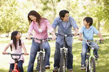 Asian family riding bikes in park