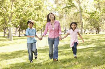 Asian mother and children running hand in hand in park