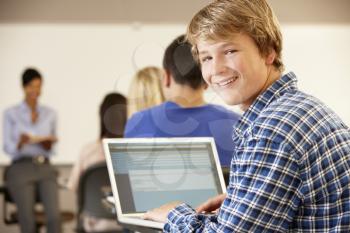 Teenage boy using laptop in class