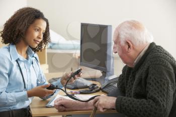 Young female Doctor taking senior man's blood pressure