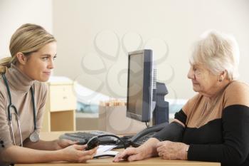 Doctor taking senior woman's blood pressure