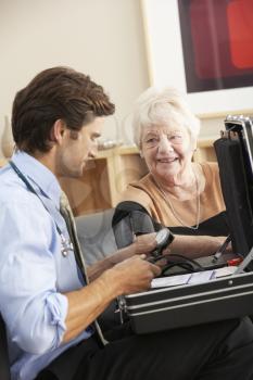 Doctor taking senior woman's blood pressure at home