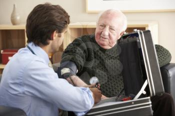 Doctor taking senior man's blood pressure at home