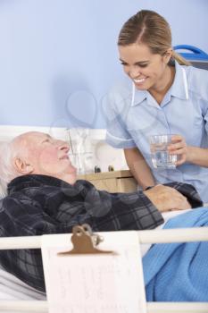 Nurse giving glass of water to senior man in hospital