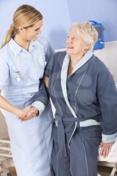 Nurse helping senior woman out of bed in hospital
