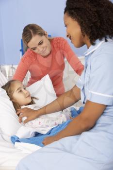 Nurse and mother at girl's bedside in hospital