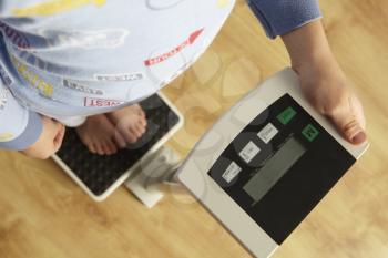 Young boy standing on digital scales cropped waist down