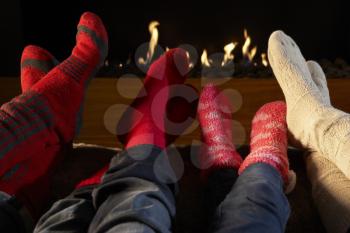 Four pairs feet in socks warming by fire