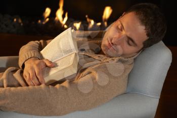Man asleep with book in front of fire