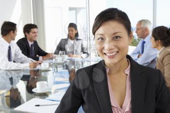 Asian Businesswoman Sitting Around Boardroom Table With Colleagues