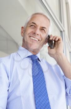 Mature Businessman Standing Outside Modern Office Talking On Phone