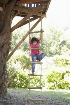 Young Boy Climbing Rope Ladder To Treehouse
