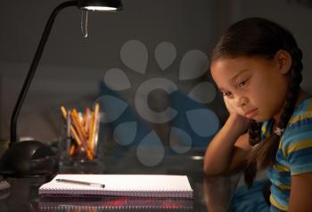 Unhappy Young Girl Studying At Desk In Bedroom In Evening